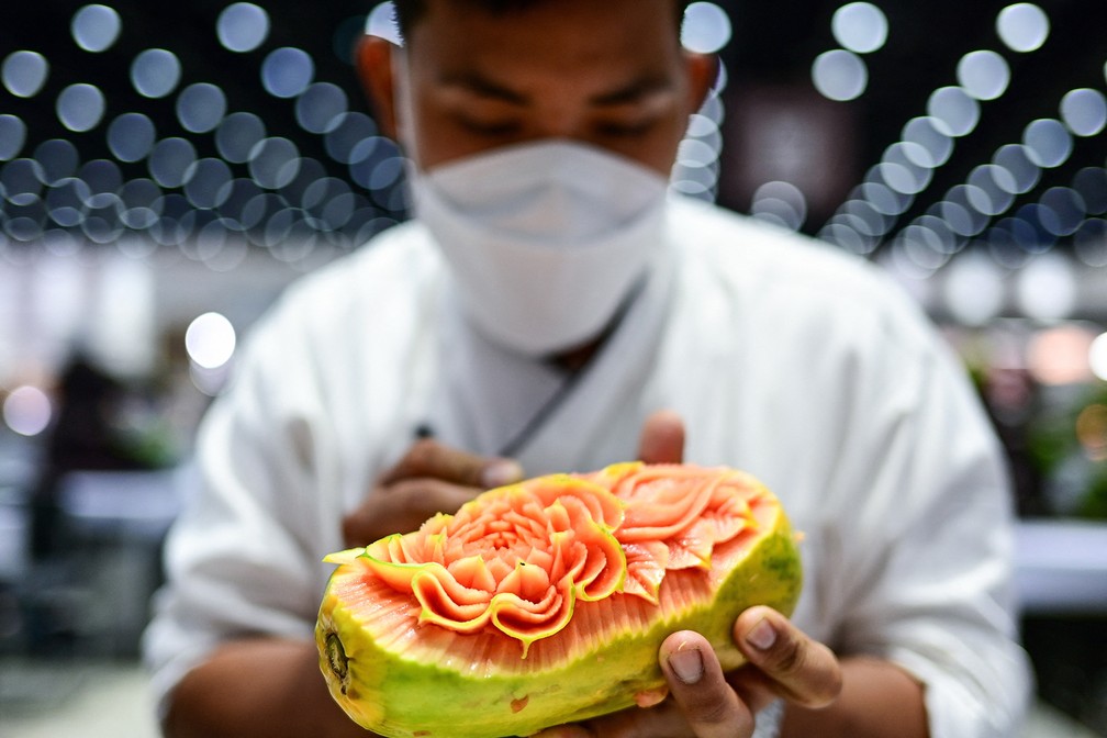 Participante tailandês esculpe um mamão durante competição que faz parte da 26ª Copa Internacional de Culinária da Tailândia — Foto: Manan Vatsyayana/AFP
